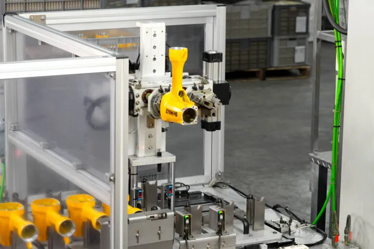 Automated production cell processing overmolded aluminum tool bodies to ensure consistent grip quality and molecular adhesion.