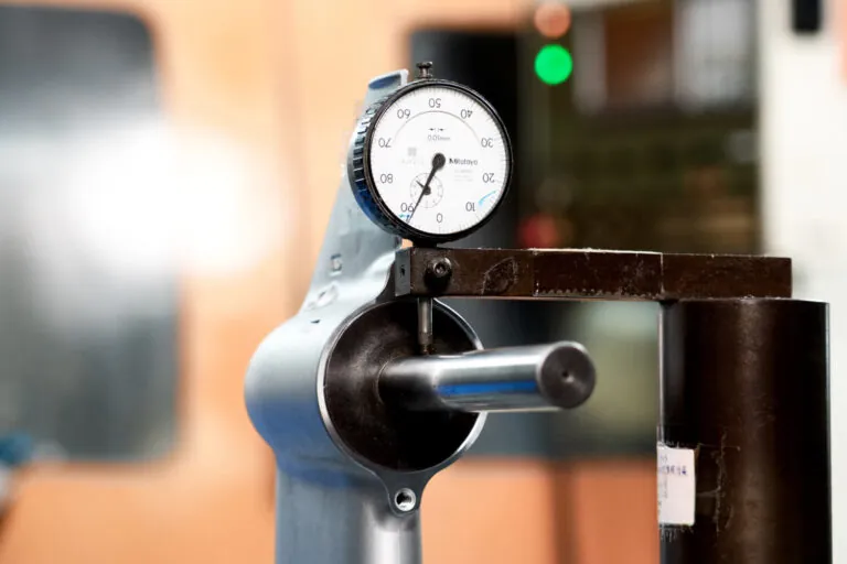 Mitutoyo precision dial indicator verifying ±0.01mm machining tolerances on a critical aluminum interface