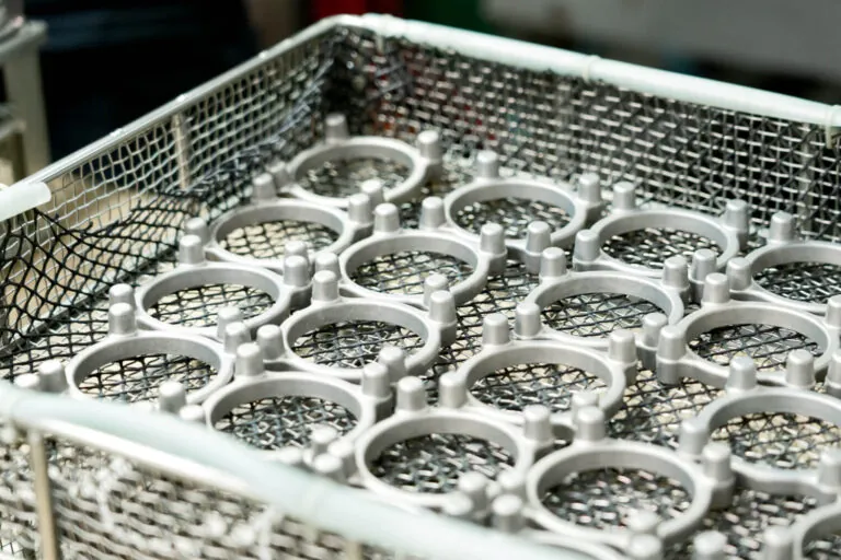 Aluminum die cast rings organized in stainless steel baskets for high-volume automated cleaning and surface preparation before final coating.