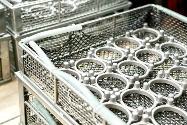 Aluminum die cast rings organized in stainless steel baskets for high-volume automated cleaning and surface preparation before final coating.