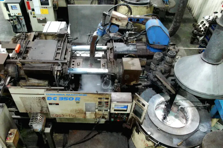 Close-up of a Toshiba high-pressure die casting machine during the extraction process, demonstrating automated high-volume OEM production.